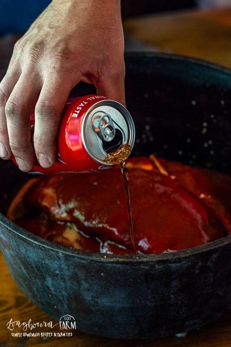 Pouring coke into the dutch oven ribs.