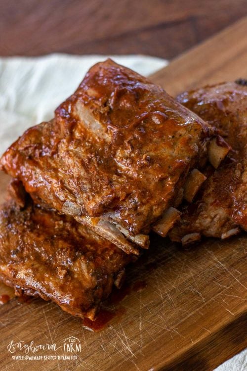 Slow cooker pork ribs stacked on a cutting board. 