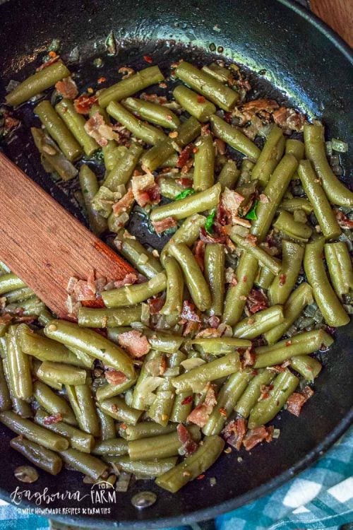canned green beans in a pan with bacon and onions. 
