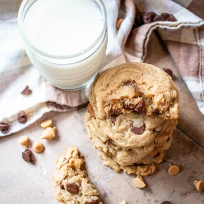 Easy chocolate chip peanut butter cookies staked next to a glass of milk, top view.