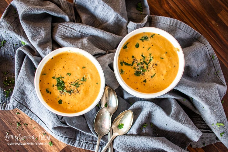 Two bowls filled with creamy pumpkin soup.