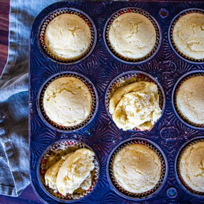 cornbread muffins in a pan with two cut open to show crumb shot