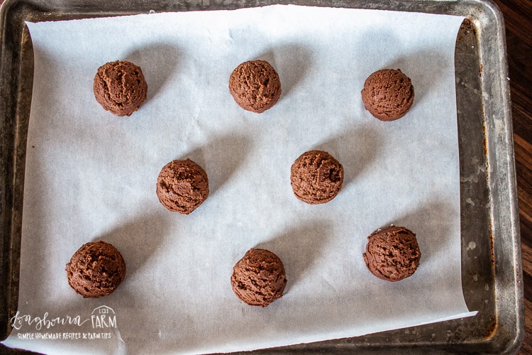 round balls of chocolate cookie dough on a parchment lined baking sheet