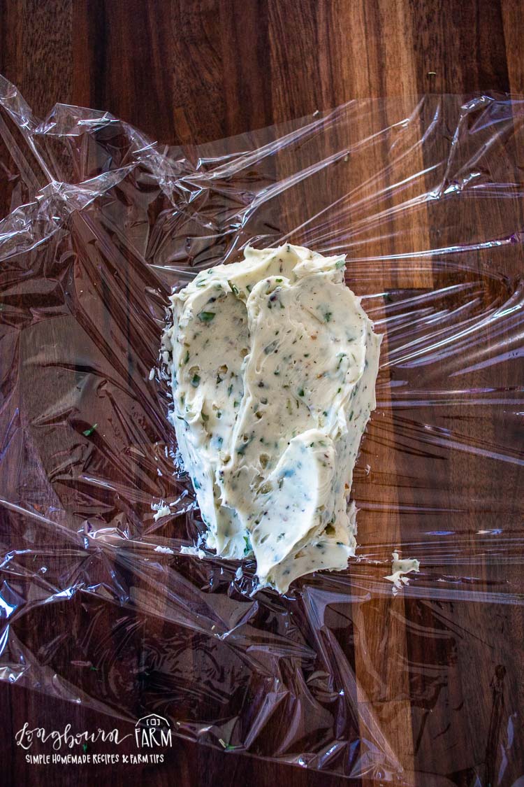 garlic herb butter spread on a sheet of plastic wrap