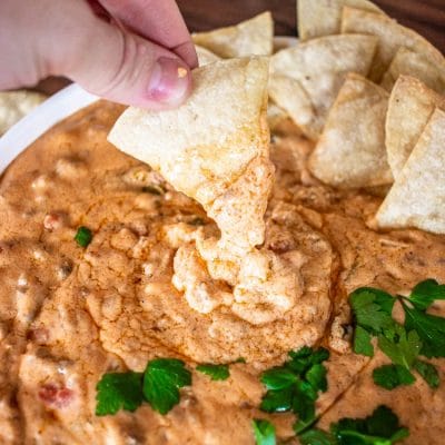 scooping some chili cheese dip with a tortilla chip