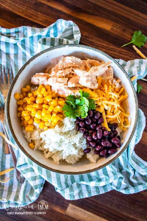 serving the mexican chicken in a bowl with cheese, corn, black beans, and white rice