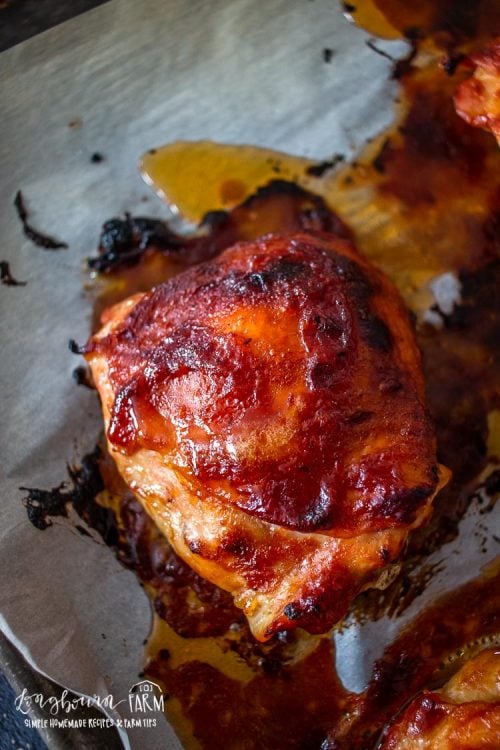 an upclose view of the baked bbq chicken thighs on a parchment lined baking sheet