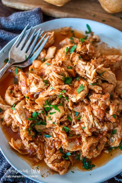 an upclose view of shredded bbq chicken and garnniches with two forks