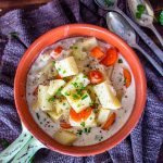 a bowl full of potato soup and carrots with three spoons off to the side