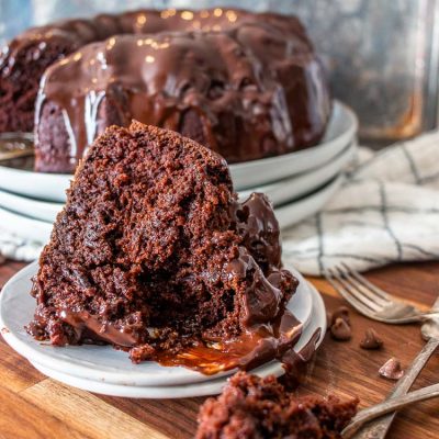 a fork full of cake infront of a slice of chocolate bundt cake in front of the rest of the whole bundt cake