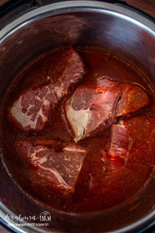 cuts of beef and liquid inside of an instant pot bowl