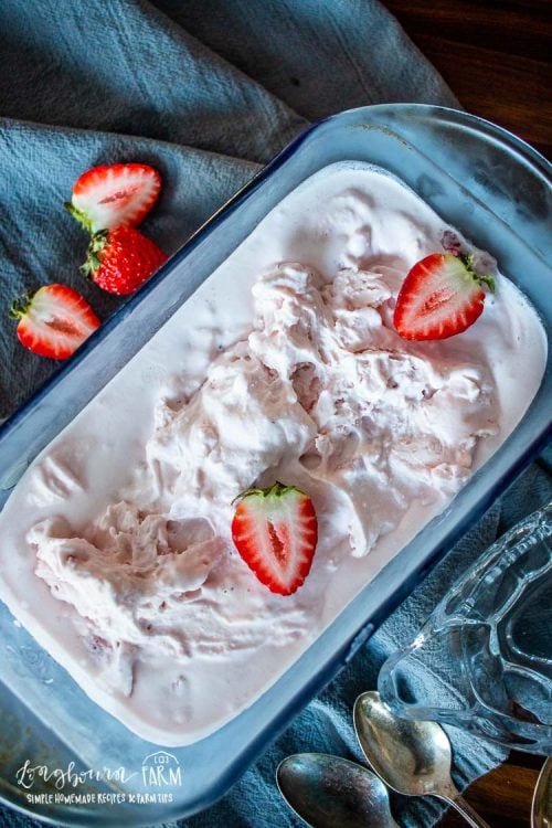 a bread pan filled with strawberry ice cream topped with fresh strawberries