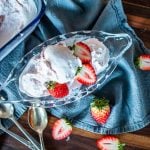 a glass bowl filled with strawberry ice cream and fresh strawberry slices