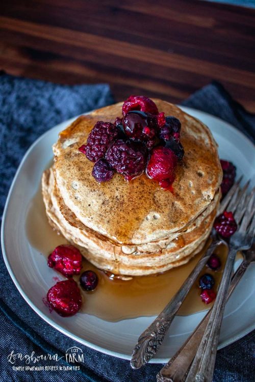 stack of whole wheat pancakes topped with syrup and fresh berries