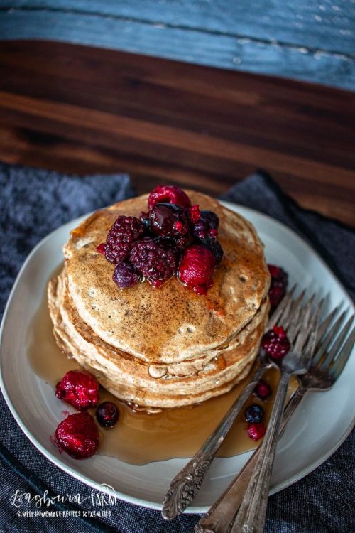 stack of whole wheat pancakes topped with syrup and fresh berrieswith three forks