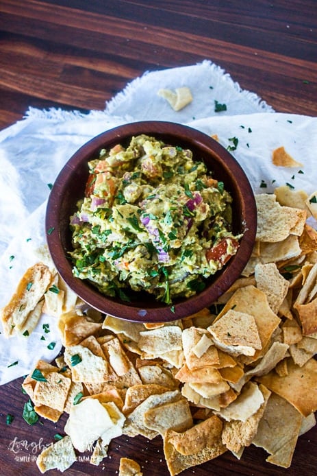 guacamole in a bowl with a pile of chips