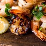 a close up view of honey garlic shrimp on a wooden cutting board with garnishes