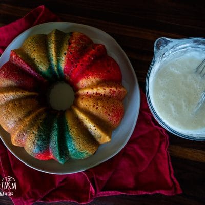 aerial view of red white and blue bundt cake next to bowl of glaze with whisk