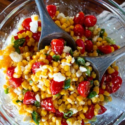 two wooden spoons in the corn tomato salad