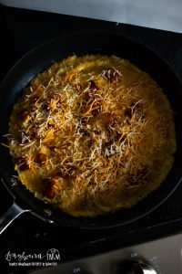 omelet in a skillet topped with filling ingredients like cheese