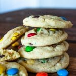Side view of stacked M&M cookies with scattered M&MS and broken cookies to the sides