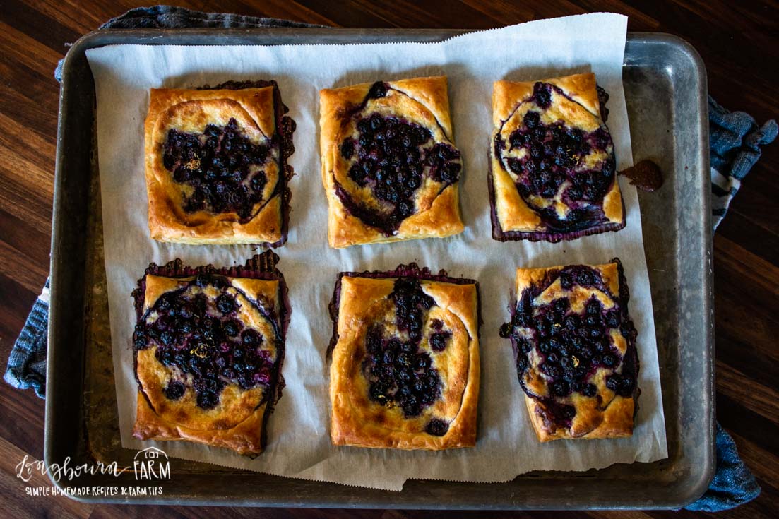 aerial view of parchment lined baking sheet with blueberry danishes on top
