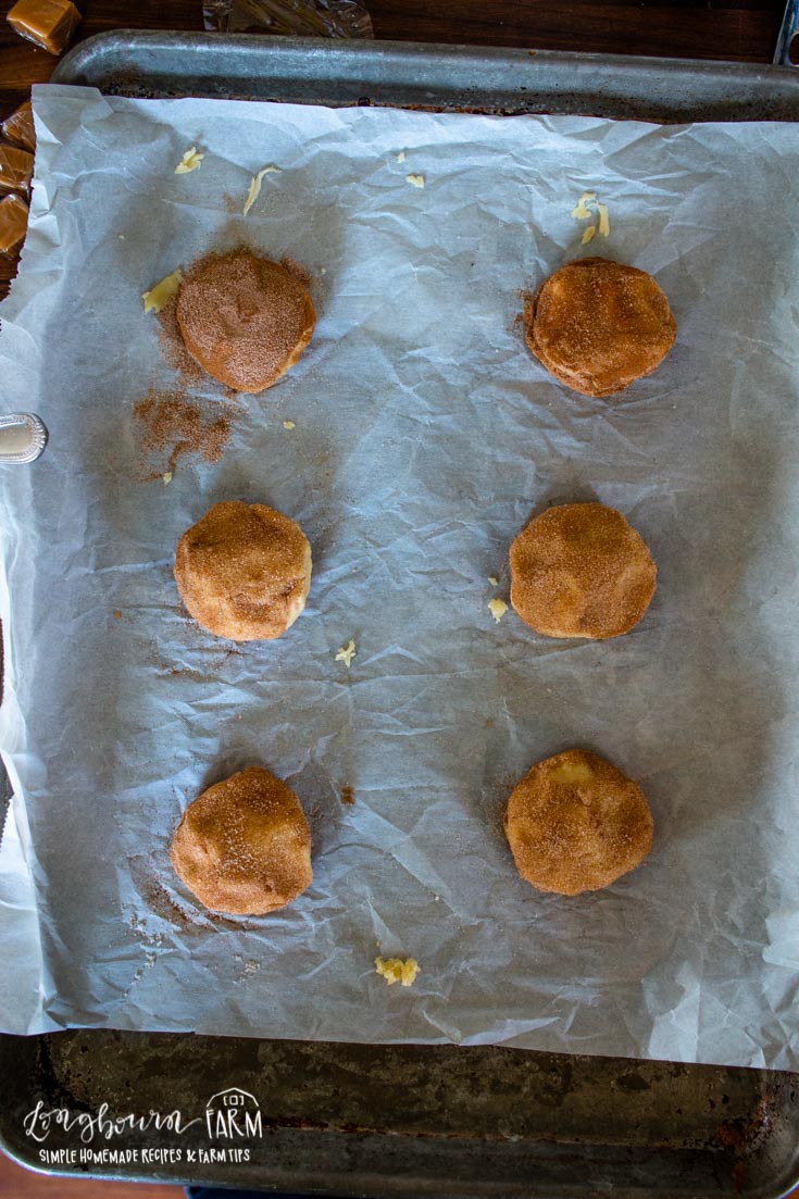 caramel stuffed snickerdoodle dough balls on a parchment lined baking sheet