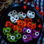 a dark plate filled with halloween pretzels of different color and themes