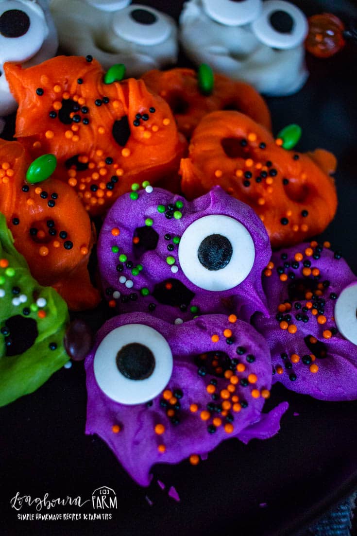 halloween pretzels with sprinkles and eyes on a dark plate