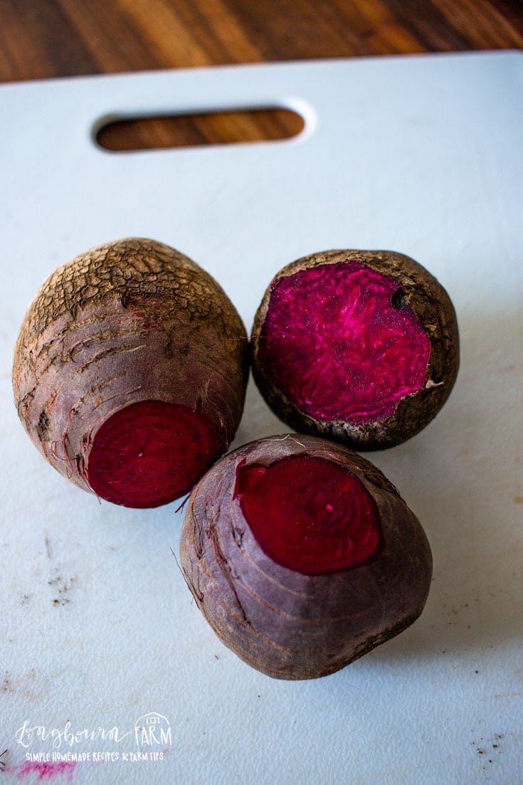 three slightly peeled beets on a cutting board