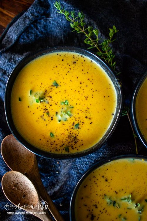 a close look at a bowl filled with carrot soup and garnished