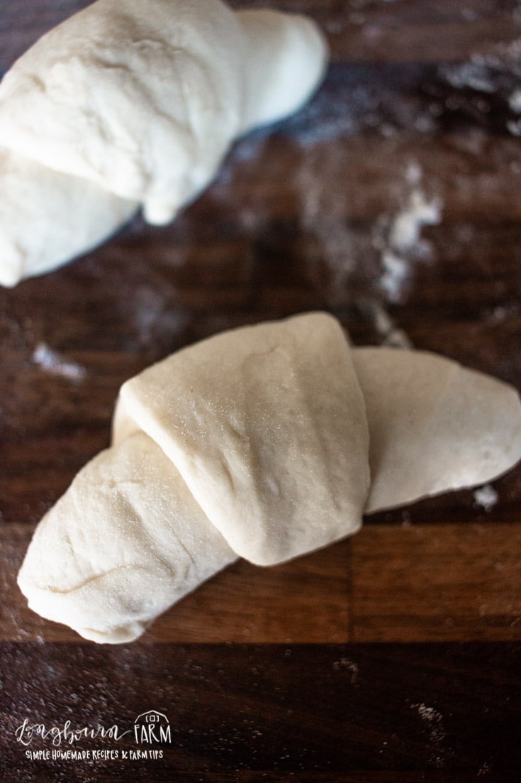 bread rolls shaped like crescent rolls on floured surface
