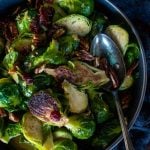 a large metal spoon in a bowl of roasted brussel sprouts with pecans
