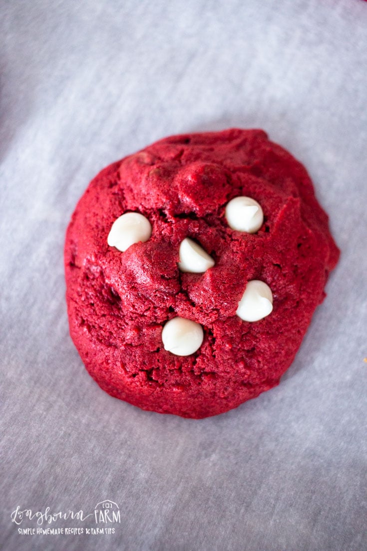 an upclose view of white chocolate topped red velvet cookie on parchment paper