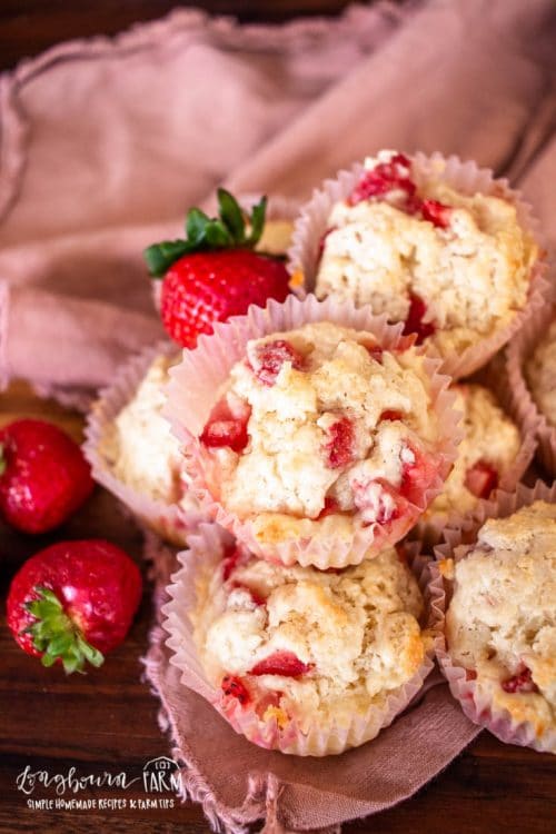 an above angled view of a stack of strawberry muffins with fresh strawberries