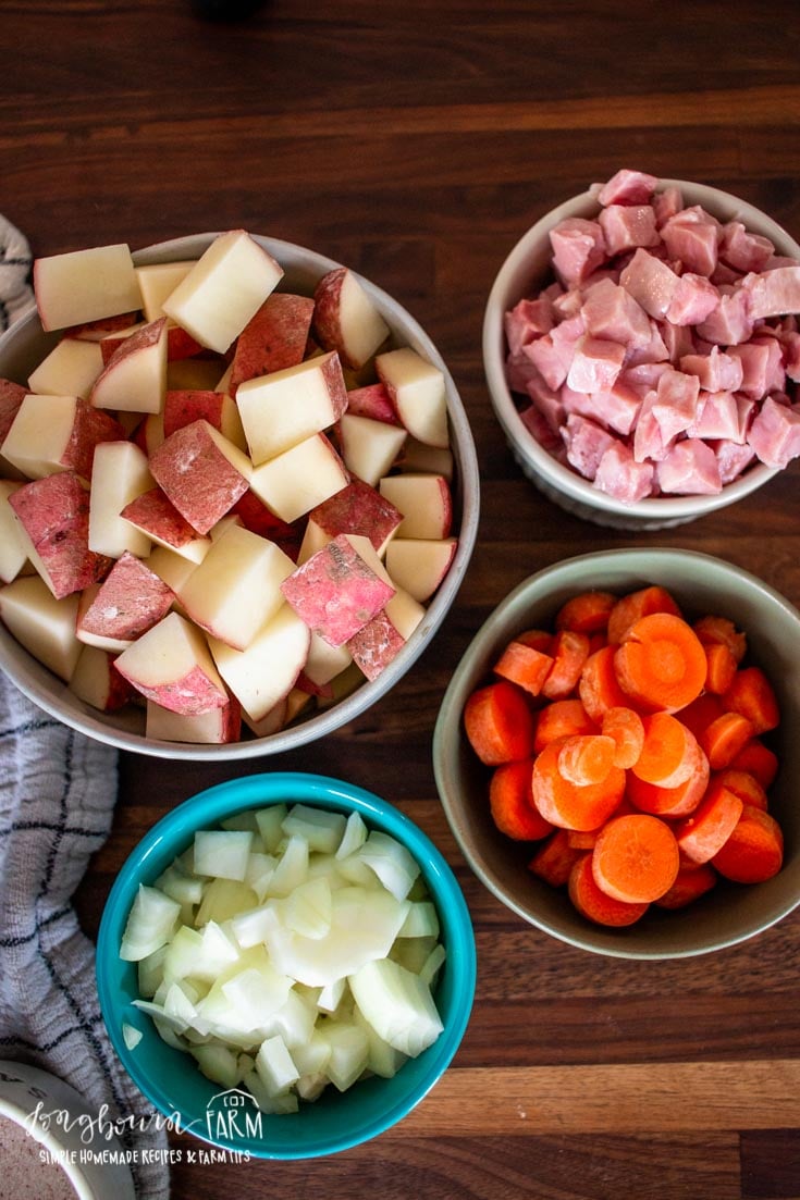 several bowls of potatoes, onion, carrot and ham diced and chopped