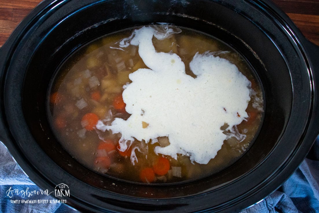 adding milk to the crockpot full of soup