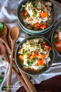 three bowls of pastina soup with three wooden spoons to the side.
