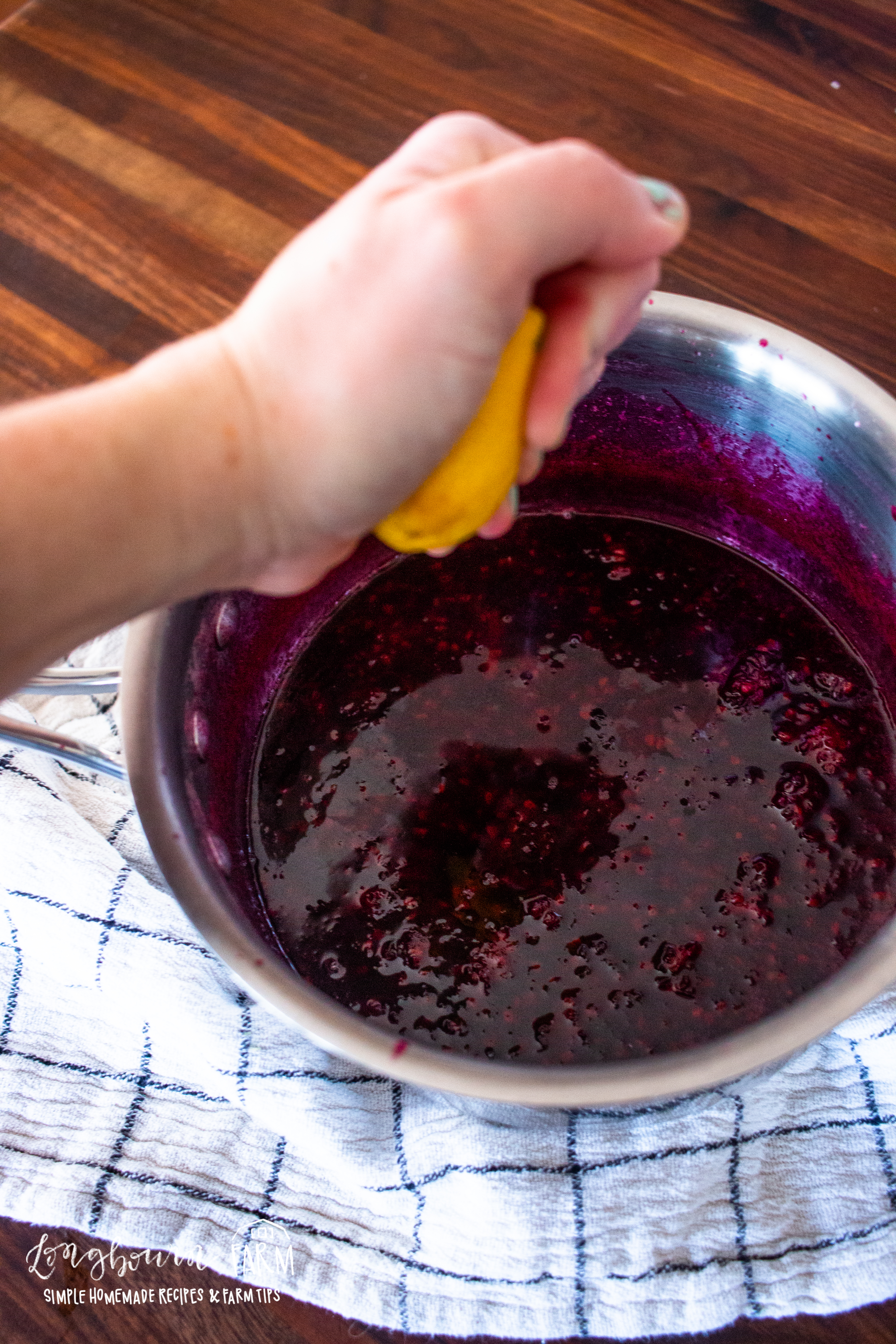squeezing lemon into the pot of blackberry syrup