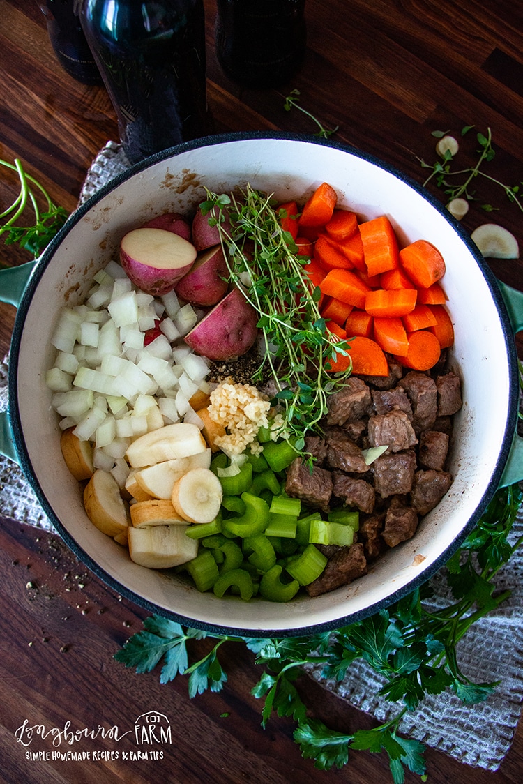 a pot full of cooked meat, veggies, and fresh herbs