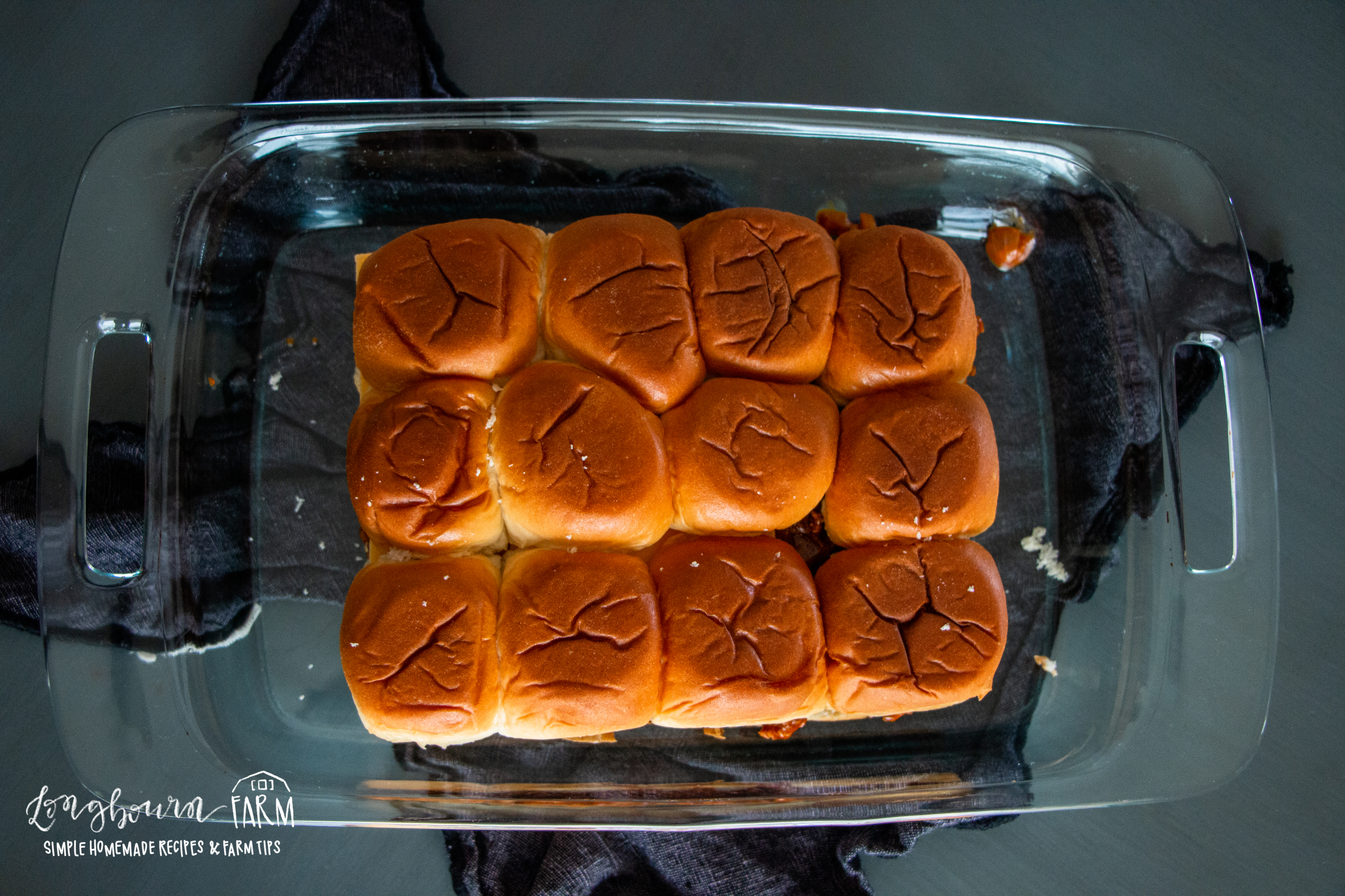 arranged and unbaked bbq beef dinner sliders in a glass baking dish
