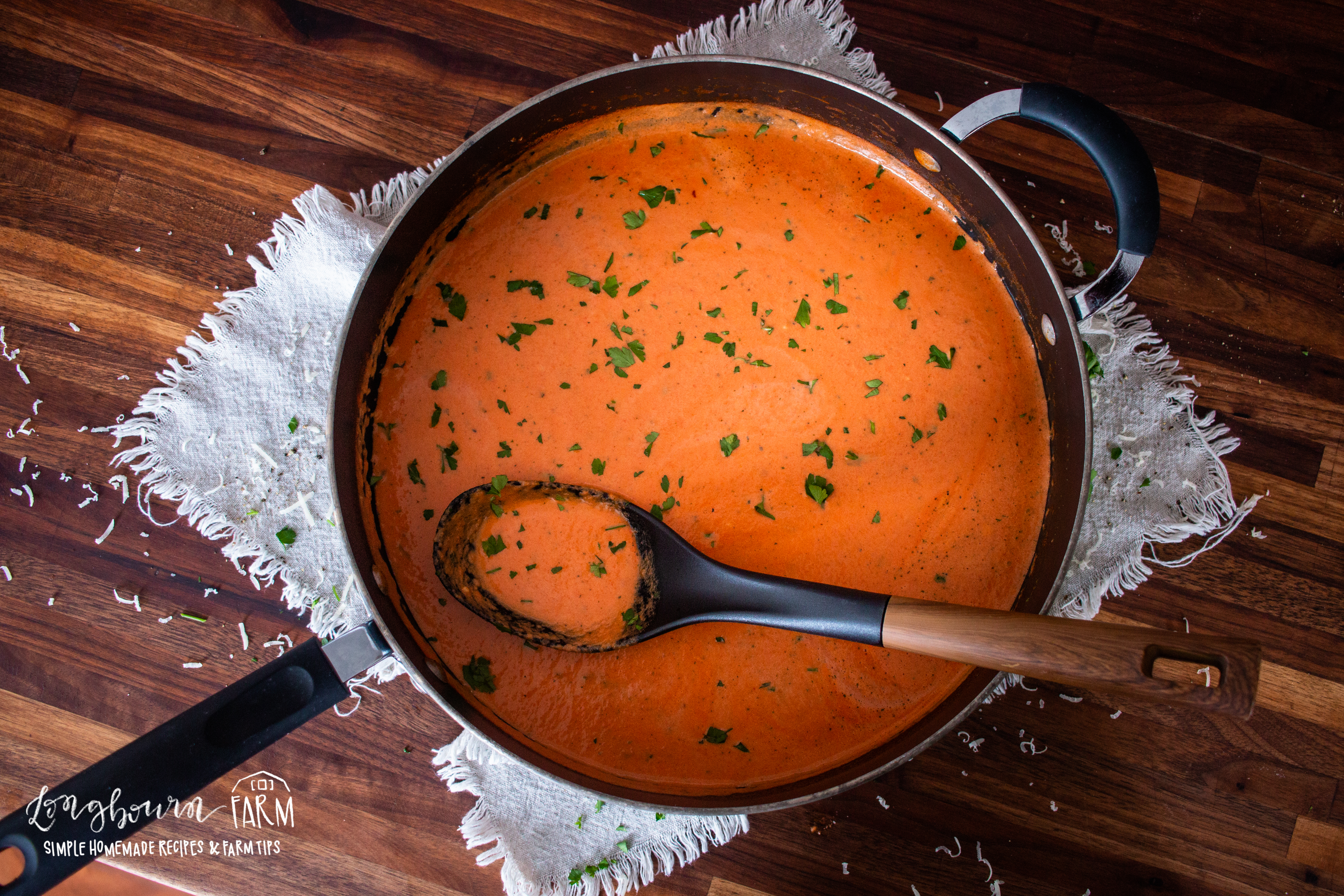 a pot filled with creamy tomato sauce with a spoon inside