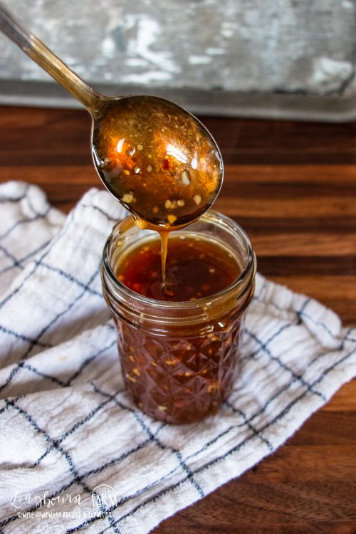 a spoon ladeling some teriyaki sauce into a glass mason jar