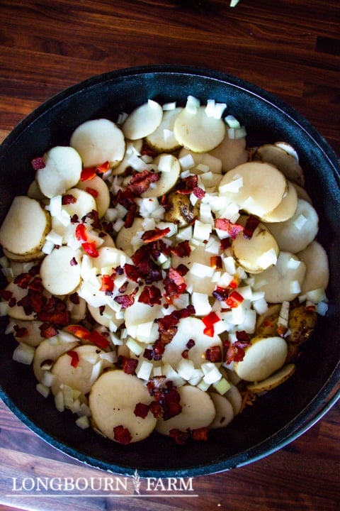 raw sliced potatoes in a dutch oven with other ingredietns