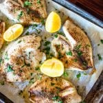 oven baked tilapia on a baking sheet with lemon wedges