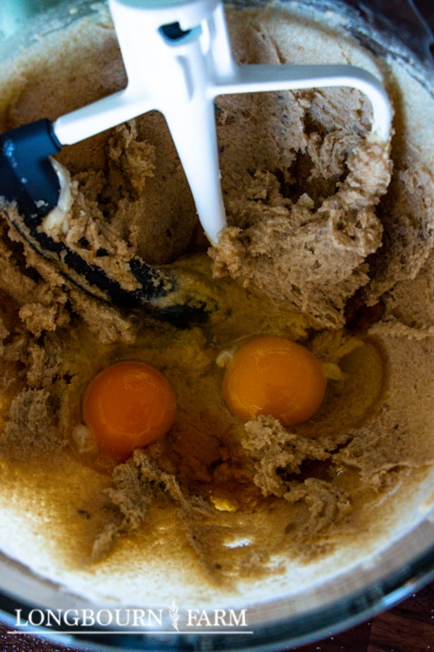beating eggs into the sugar butter mixture in a mixing bowl with paddle attachment