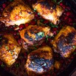 cooked chicken thighs and cranberries in a cast iron skillet