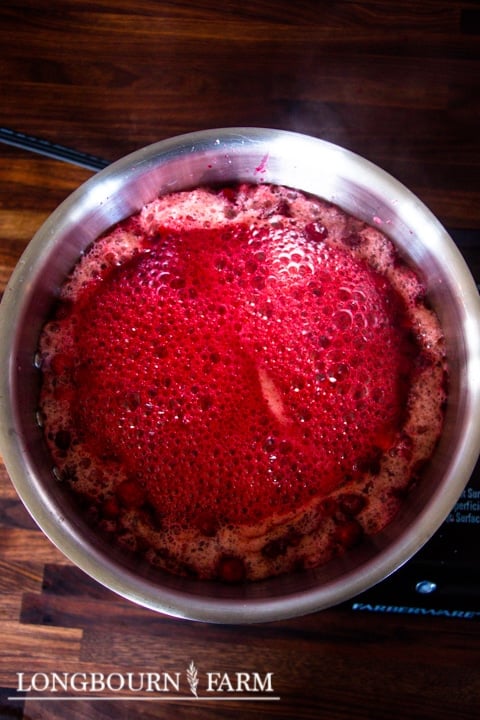 cooking cranberry sauce in a metal pot bubbling