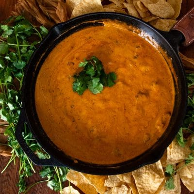 velveeta queso dip in a cast iron skillet garnished with fresh herbs