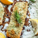 baked salmon with an herb crust with lemon wedges